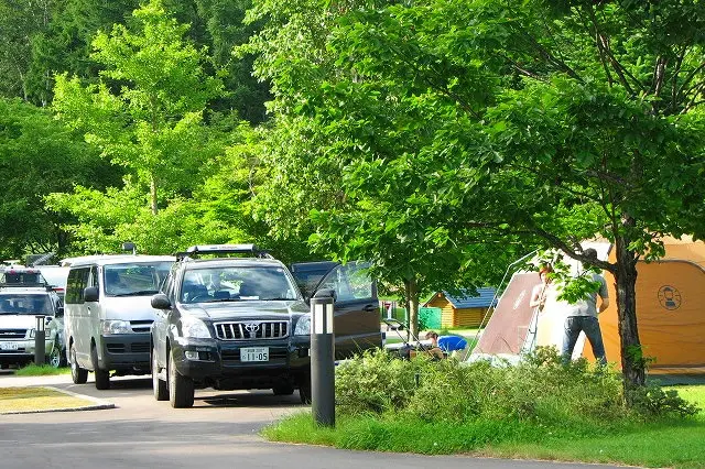 てんとらんどオートキャンプ場：木陰の区画に停めた車とテント